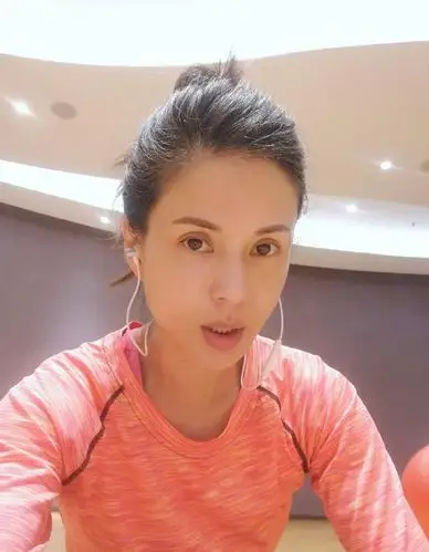"照片中,李若彤身穿粉色紧身运动衣,戴着耳机,扎着丸子头,一脸素颜
