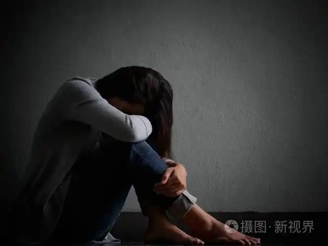 悲伤的女人抱着她的膝盖和哭泣.悲伤的女人独自坐在空荡荡的房间