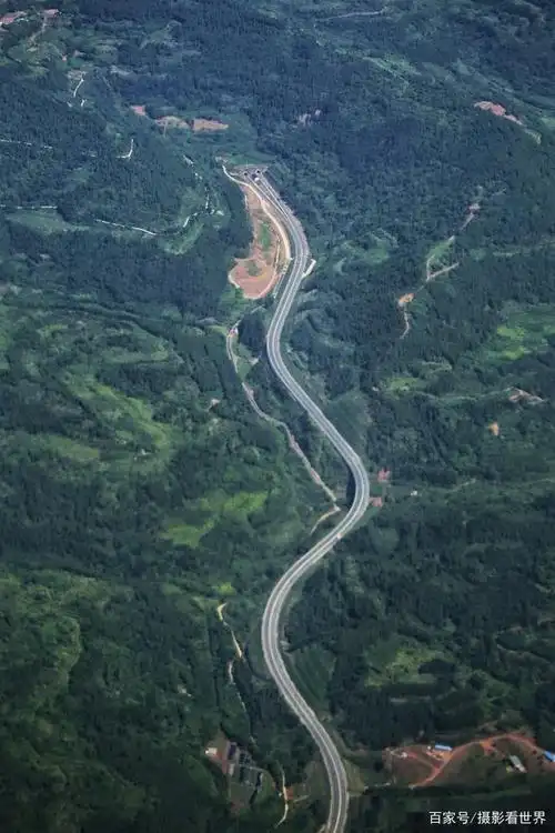 这是飞机上俯视一条高速公路的场景,像一条蛇,蜿蜒在田野间.