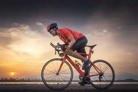 骑自行车运动健身运动员骑自行车在一条通往日落的开放道路上.照片