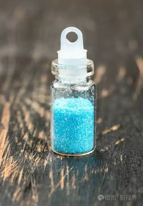 蓝色的闪光在木制背景上的一小瓶中