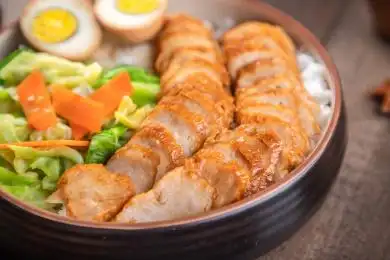 棕色木纹桌上放着一碗肉卷盖饭