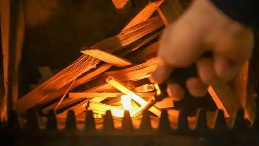 在炉子里生火, 雄性手用打火机点燃一堆柴火照片