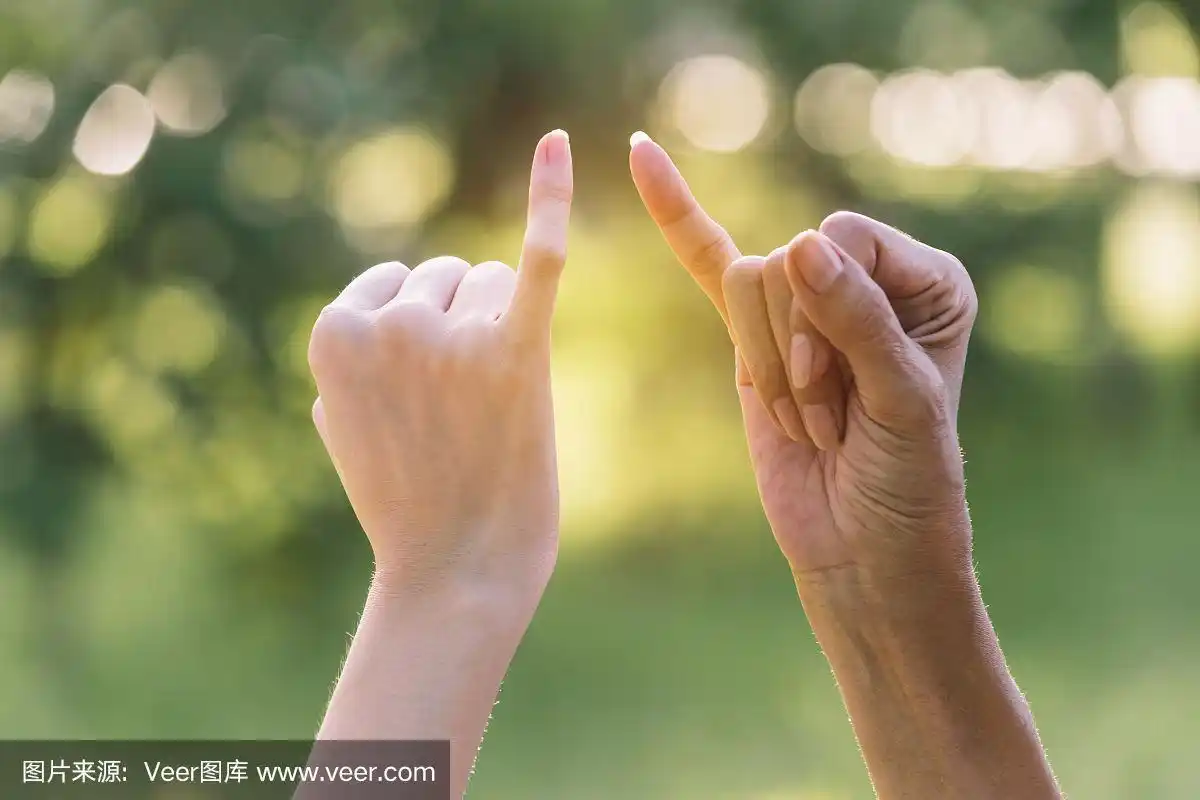 特写两个人在自然背景上勾住对方的小指.