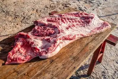 新鲜宰杀的半边猪肉在木案板上