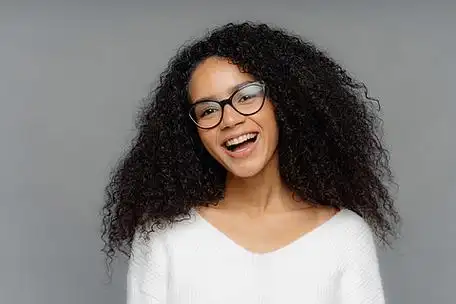 无忧无虑,喜出望外的黑皮肤女人开心地笑着,精神振奋,歪着头,有一头