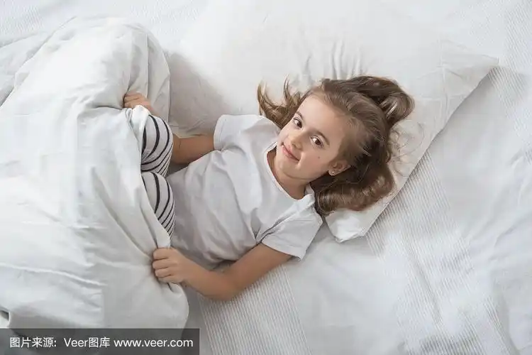 可爱的小女孩早上在床上醒来.