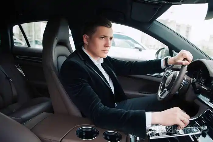 侧面视图肖像的英俊残酷严肃的年轻商人坐在车里, 开车到他的巨大的