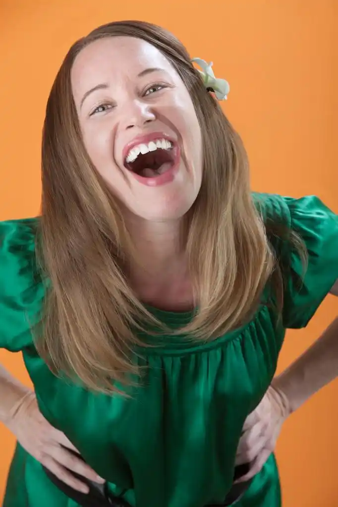 女人大声笑,美丽的白种女人大笑出橘黄色的背景上