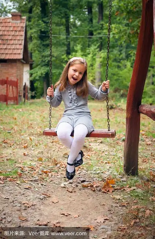 快乐的小女孩在秋千上微笑