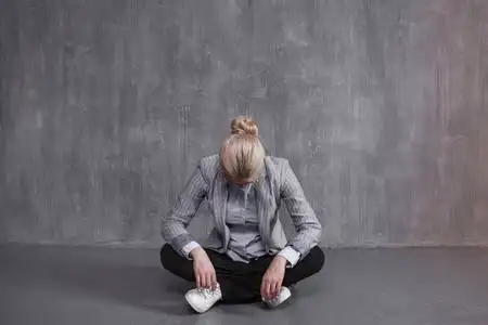 倦怠疲劳, 职业倦怠.穿着西装的年轻女子坐在莲花姿势, 低头照片