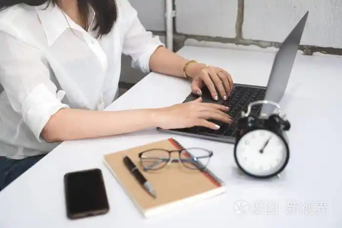 照片 年轻女子使用笔记本电脑在家庭办公室的白色桌子上工作,带智能