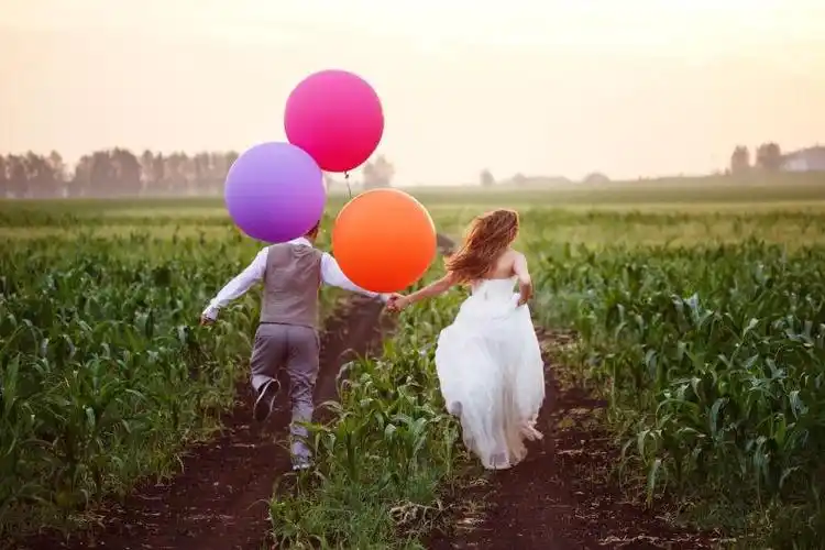 在日落时拥抱亲吻的新婚夫妇