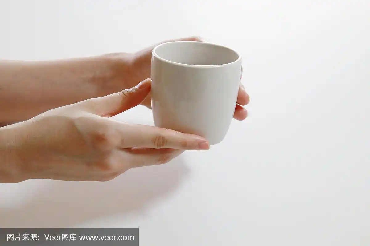 一只手拿着一只盛着果汁的白色杯子