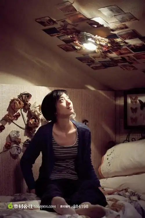 坐在床上仰头看照片的清纯女孩电影剧照