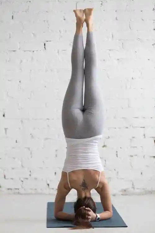 年轻漂亮的女人倒立瑜伽姿势