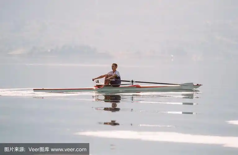 一位年轻的单人赛艇选手在宁静的湖面上划桨