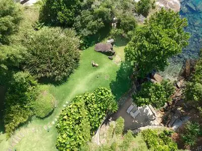 鸟瞰豪华住宅花园在热带森林周围的树木和旁边的海洋和蓝色绿松石水.