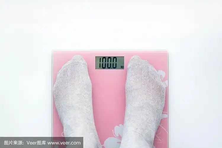 一个男人用浴室秤称体重.显示100公斤.从上面的观点