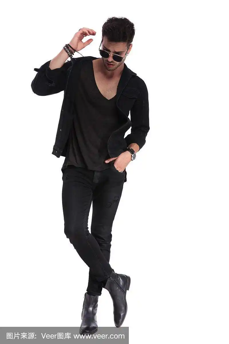 放松的男人,双腿交叉站着,向下看