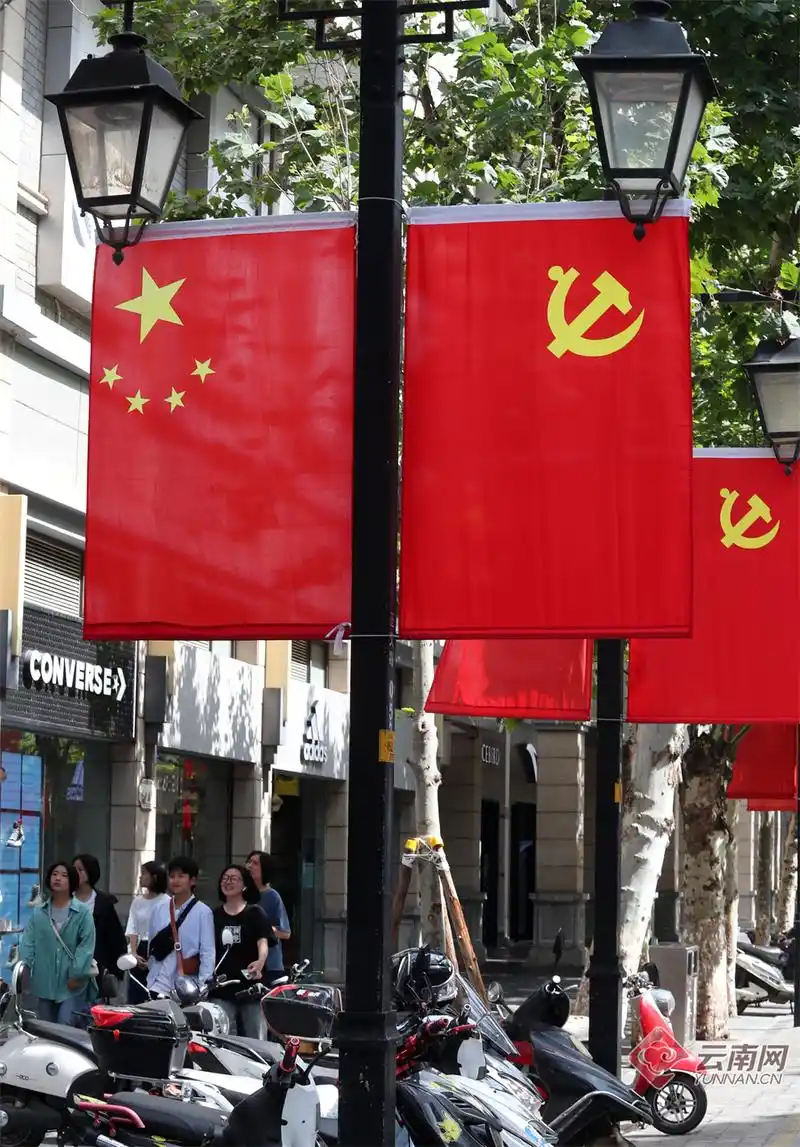 在昆明正义路街区,道路两侧灯杆已用鲜艳的国旗和党旗进行了装点,整条
