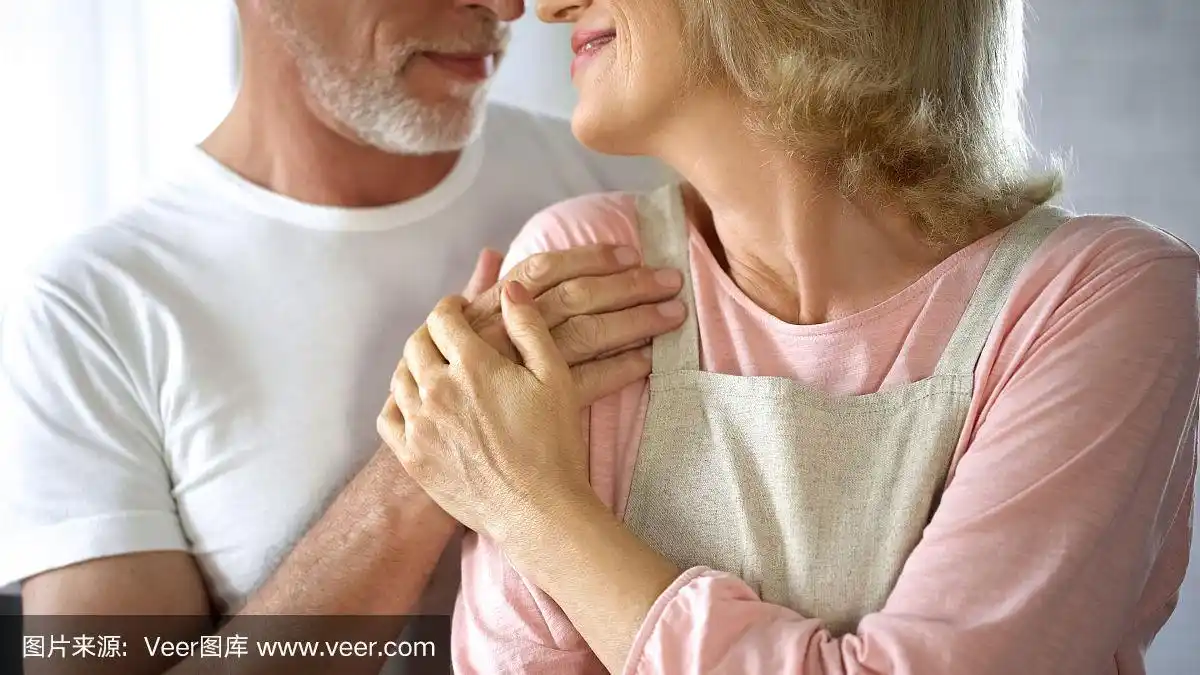 有爱心的老人拥抱着穿着围裙的妻子,家人的支持和关怀,幸福的婚姻