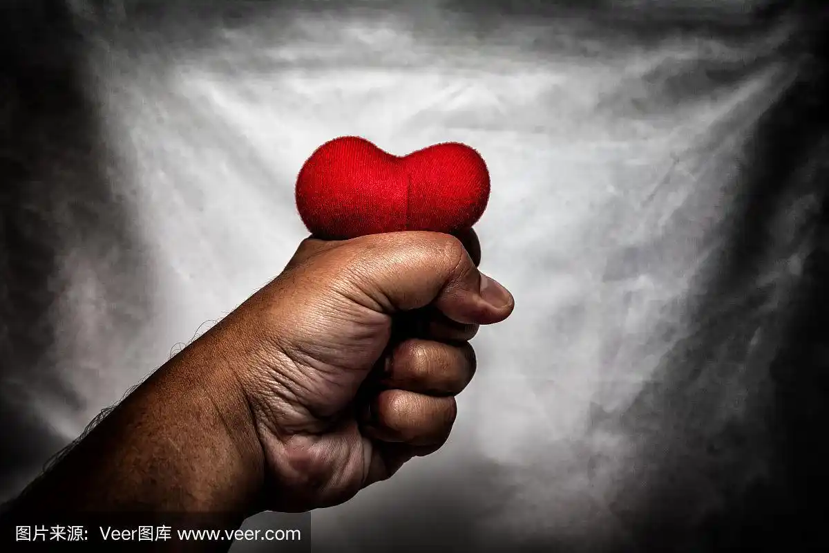 愤怒的男人捏碎了手里的红心.,暗恋.,这是情人节的爱情概念.,暗色调.