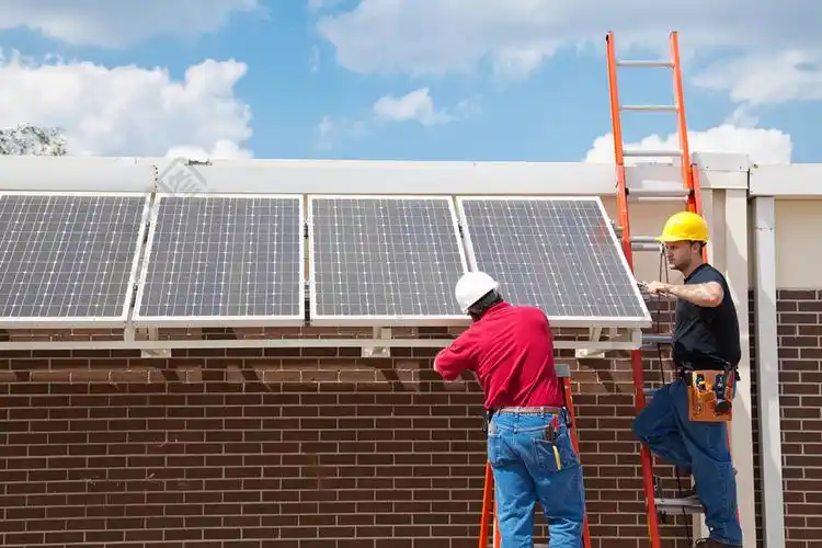 工人在建筑物的一侧安装太阳能电池板具有文本空间的广角视图