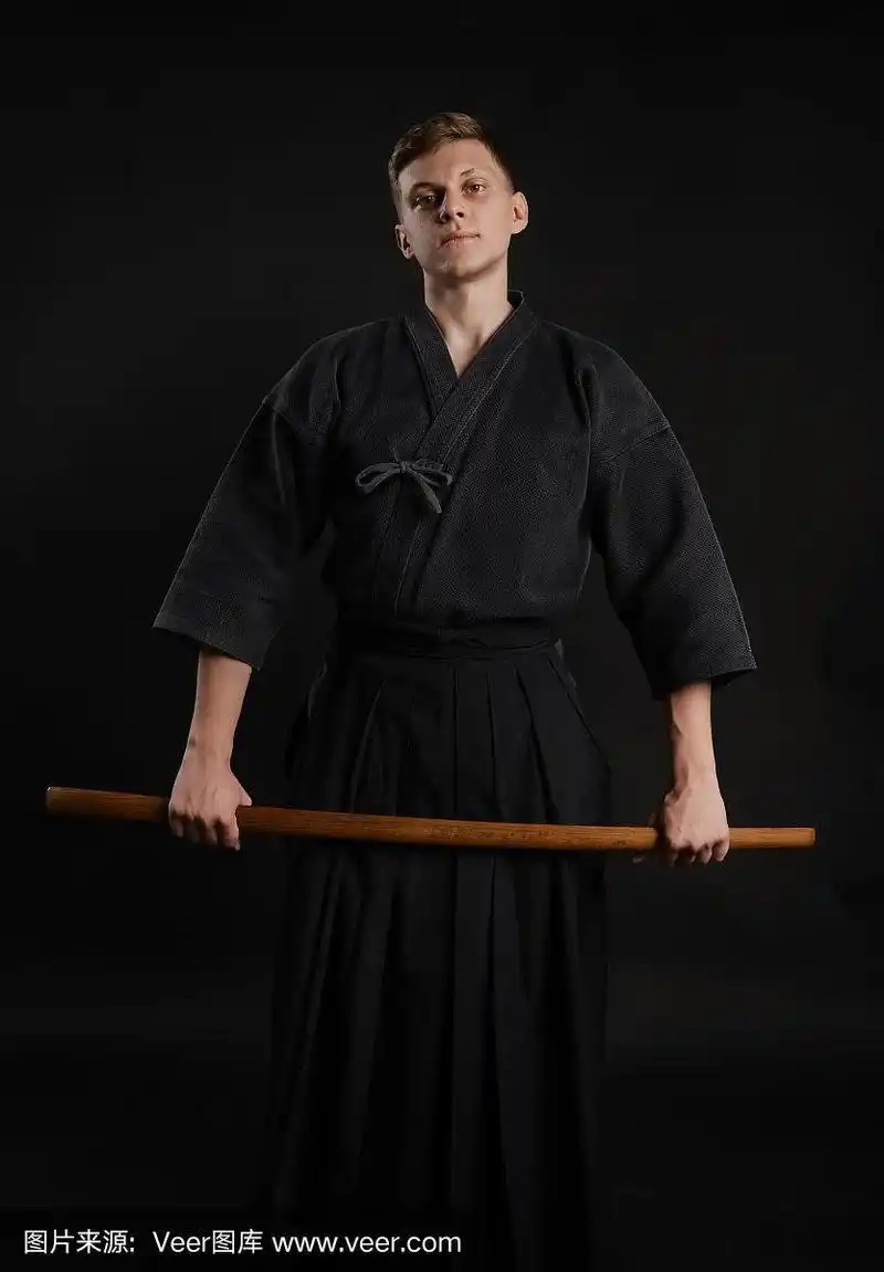 剑道大师穿着传统的日本和服正在练习武术与shinai竹剑在一个黑色的