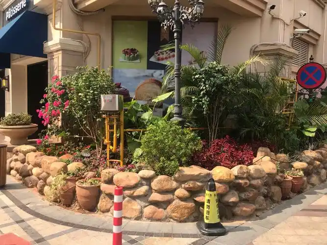 一块块整石堆砌的花坛,石缝中夹杂着各式各样的花钵,十分有趣.