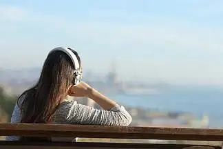 一个放松 i>的 /i>女 i>人 /i>戴着耳机听音乐,思考城市郊区景色 i>的