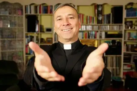 一个漂亮的天主教神父张开双手, 献上基督的喜乐.