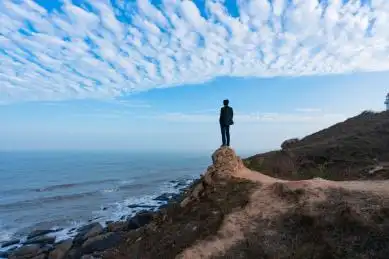 一个亚洲成年男子站在海边眺望远方