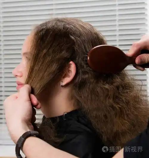 理发师梳的女孩卷曲的头发棕色刷子