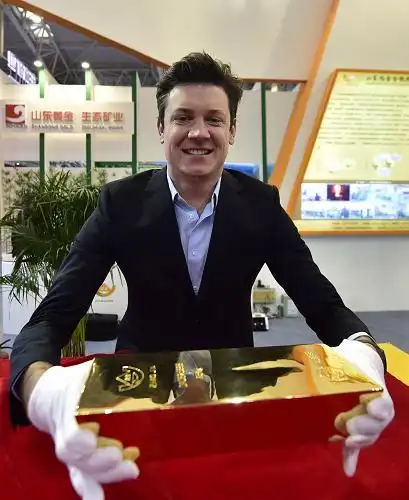 10月21日,一名参会人员手持一家企业展出的重达25公斤的金砖.