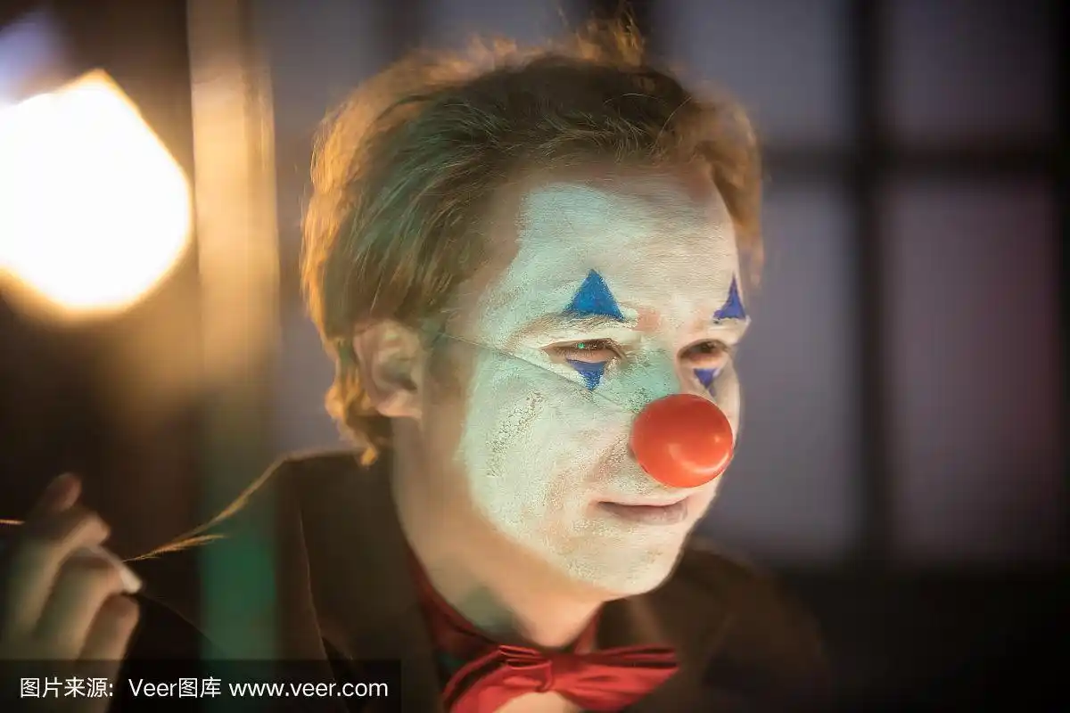 小丑概念——一个人画着一张脸看着镜子