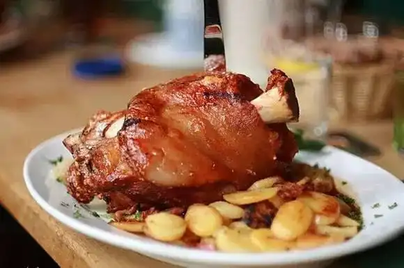 煮熟晾凉后的猪肘用铁钎在表皮上扎出许多小孔,这样烤出来的肘子皮才