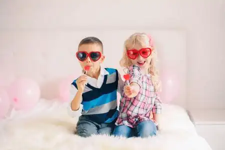 两个快乐的白色白种人可爱可爱有趣的孩子吃心形棒棒糖的团体肖像.