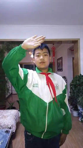 (少先队员立正,面向视频中的国旗行队礼,在场家长行注目礼)