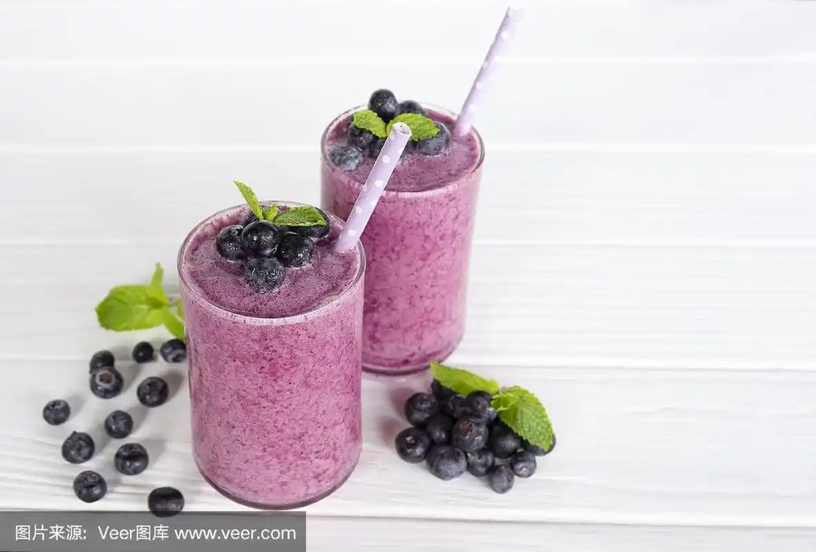 蓝莓果汁,一种美味的健康饮料在一杯饮料早上在白色的木制背景.