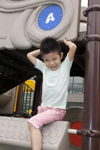 小男孩在幼儿园内玩滑梯