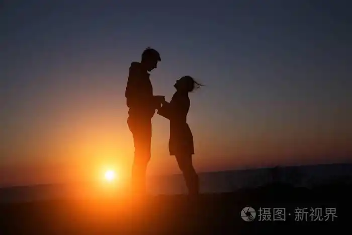 剪影男孩和女孩在一个美丽的黄昏,手牵着手