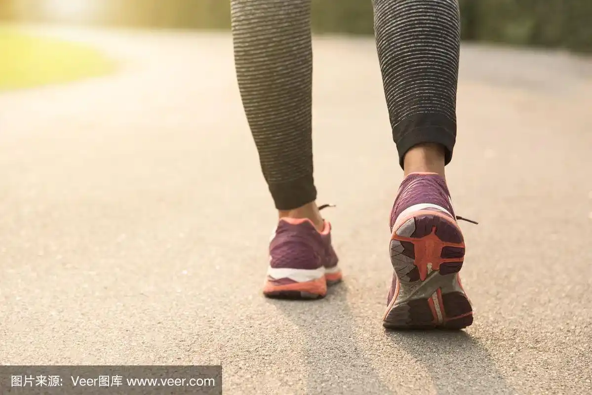 年轻的女跑步者在日落背景下的道路上慢跑.健康的生活方式的概念.