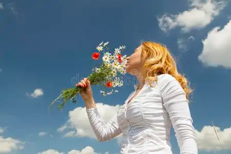 一个三岁小女孩的肖像在花园里闻花香年轻女子走在盛开的向日葵地里
