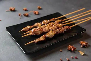 室内黑色桌子上的一盘烧烤鸡心