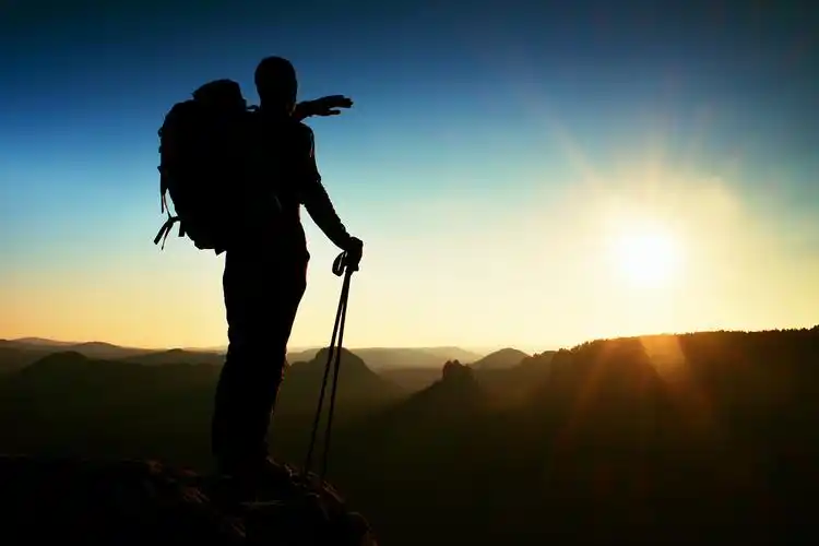 徒步旅行者登上山顶看日落锋利的高个子山顶与太阳在框架中的剪影.