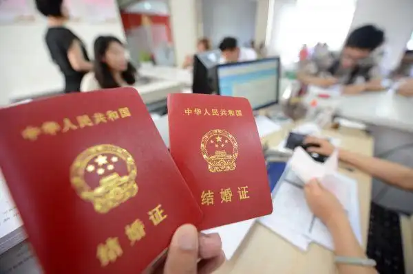 资料图片:新人在江苏扬州市广陵区民政局展示刚领取的结婚证.