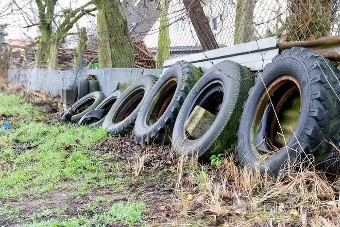 不同大小的旧轮胎靠在篱笆上