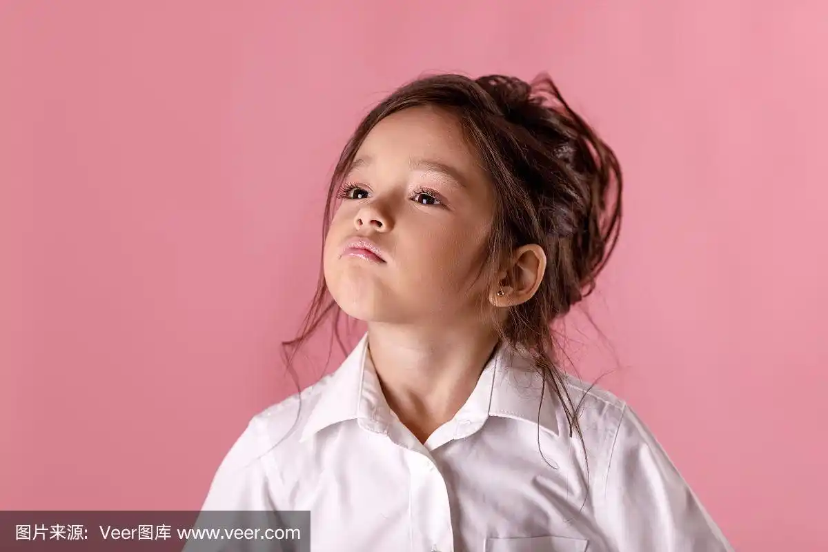 可爱骄傲的小女孩穿着白色衬衫,粉红色的背景.人类的情绪和面部表情