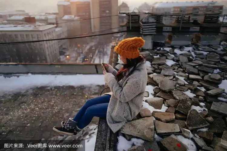 一名年轻女子坐在屋顶上玩智能手机